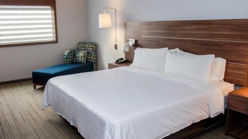 a hotel room with a large bed and a chair at Holiday Inn Express & Suites - Ciudad Obregon by IHG in Ciudad Obregón