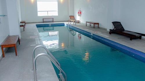 una piscina con bancos y sillas en un edificio en Holiday Inn Express & Suites - Ciudad Obregon, an IHG Hotel en Ciudad Obregón