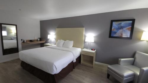 a hotel room with a bed and a chair at West Valley Inn in West Valley City