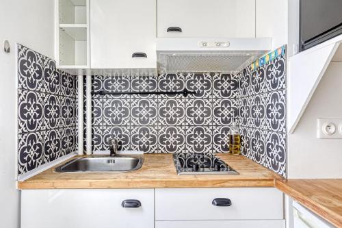 una cocina con fregadero y una pared de azulejos en blanco y negro. en Le Zen - Proche Paris et Aéroport d'Orly, en Alfortville
