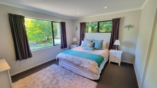 a bedroom with a bed and two windows at 5b Torquay Tce in Hanmer Springs