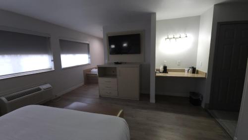 a bedroom with a bed and a sink and a television at West Valley Inn in West Valley City