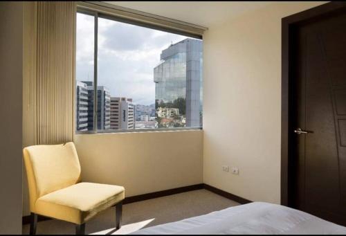 a bedroom with a chair and a large window at Suite bussines half of the world 12 in Quito