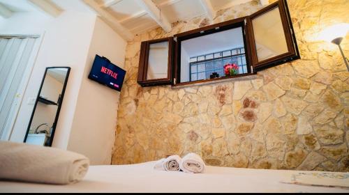 a bedroom with a stone wall with a window at Albergheria little home in Palermo