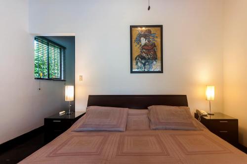 1 dormitorio con 1 cama grande y 2 mesitas de noche en Casa Gris in Jaco, en Jacó