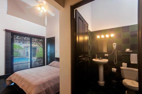 a bathroom with a bed and a sink and a toilet at Casa Gris in Jaco in Jacó