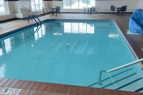 a large swimming pool with blue water in a building at Duluth Inn & Suites Near Spirit Mountain in Duluth