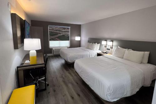 a hotel room with two beds and a yellow chair at Comfort Inn & Suites Houston West-Katy in Katy