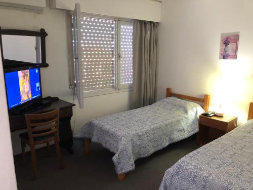 a bedroom with a bed and a desk and a television at Hotel Gaudí in Punta del Este