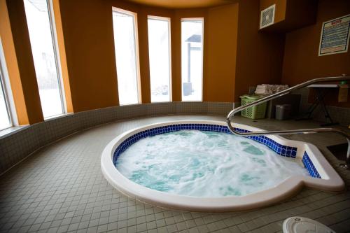 uma banheira de hidromassagem na casa de banho com janelas em SureStay Plus Hotel by Best Western Lethbridge em Lethbridge