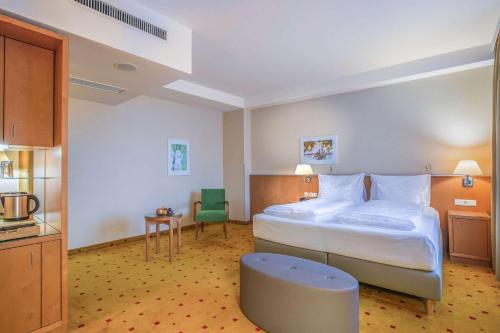 ウィーンにあるQuality Hotel Viennaの大きなベッドと椅子が備わるホテルルームです。