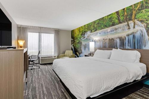 a hotel room with a bed and a waterfall mural at Clarion Pointe by Choice Hotel in Erie