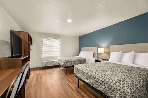 a hotel room with two beds and a flat screen tv at WoodSpring Suites Port Orange - Daytona Beach in Port Orange