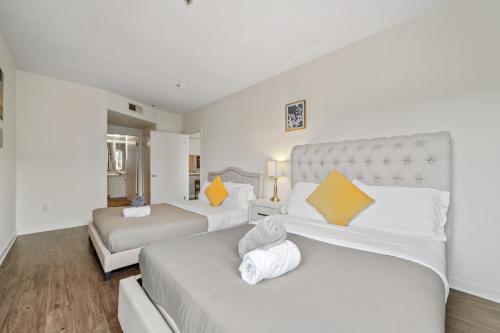 two beds in a room with white and yellow pillows at Heart Of Santa Monica , Orange Pearl Condo in Los Angeles
