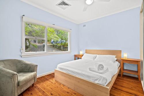 a bedroom with a bed and a chair and a window at Leafy Family House, Close to Beach and Surf Club in Macmasters Beach