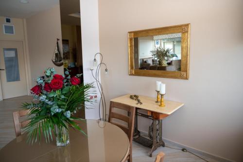 a table with a vase of flowers and a mirror at Kronos Hotel in Heraklio Town