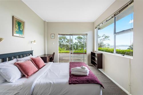 a bedroom with a large bed and a large window at Harbour Retreat with sea views and BBQ in Whangaparaoa