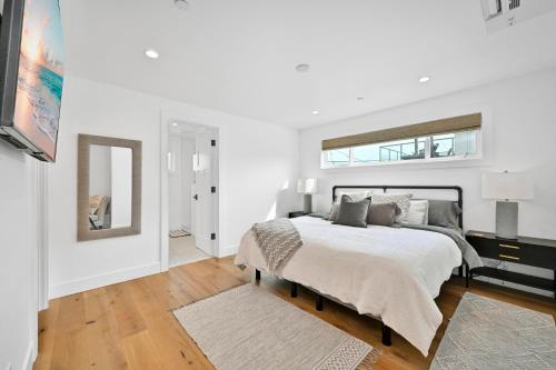 een witte slaapkamer met een bed en een spiegel bij 4 Bedrooms in BRAND NEW Luxury built Home walk to the beach in Newport Beach