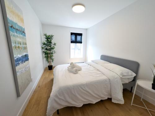 Un dormitorio blanco con una cama con un animal de peluche. en Superb 2 BedR Haven 2mins from Frontenac Metro! en Montreal