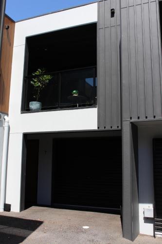 ein Gebäude mit zwei Garagentüren und einer Topfpflanze in der Unterkunft CBD Elizabeth St Modern Townhouse - Secure Parking in Launceston