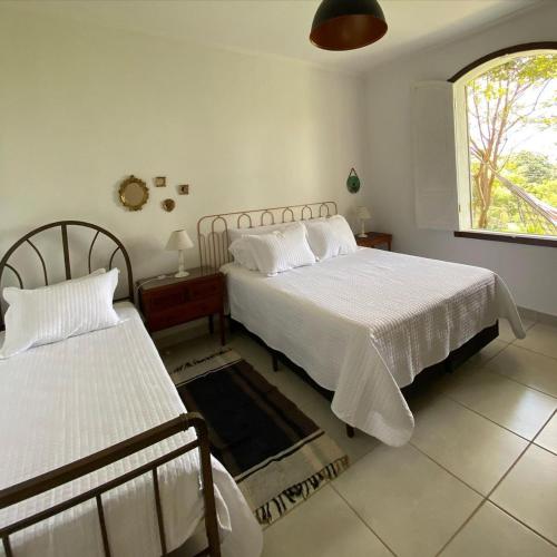a bedroom with two beds and a window at Quinta Vogrande no bairro de Águas Santas entre Tiradentes e São João Del Rey in Tiradentes