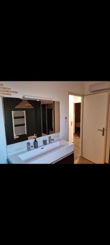 y baño con lavabo blanco y espejo. en Maison 8 couchages PORT LA NOUVELLE accés plage à pied en Port-la-Nouvelle