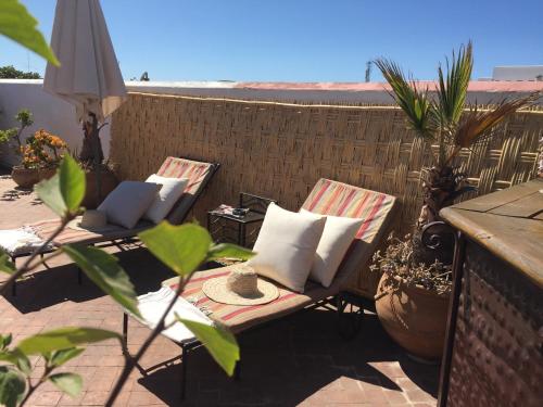 a patio with two lounge chairs and an umbrella at Riad Marhaba in Rabat