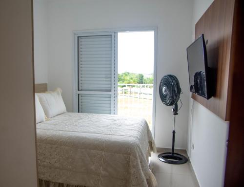 1 dormitorio con 1 cama, ventilador y ventana en Apartamento Primavera, en Boituva