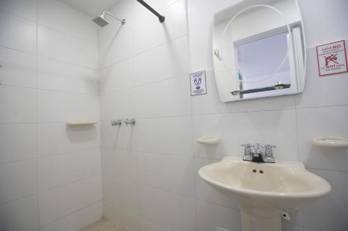 Baño blanco con lavabo y espejo en Posada Dima Cresida, en San Andrés