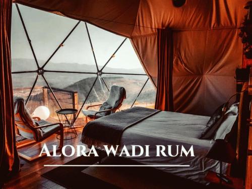a room with a bed and chairs in a tent at Alora Wadi Rum Luxury in Wadi Rum