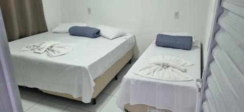 two beds in a room with white sheets at Nathus Hotel in Chapadão do Sul