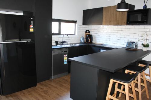 eine Küche mit schwarzen Schränken und einer schwarzen Arbeitsplatte in der Unterkunft CBD Elizabeth St Modern Townhouse - Secure Parking in Launceston