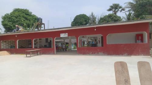 a red building with a bench in front of it at CAMPAMENTO CHEZ CAMPOS in Cap Skirring