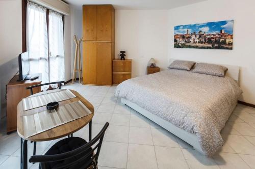 a bedroom with a bed and a table and a television at Loft alto con vista su Città Alta in Bergamo