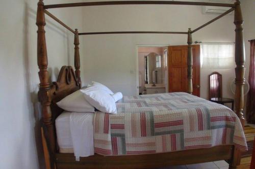 1 dormitorio con 1 cama grande con marco de madera en Paradise Getaway en Calivigny