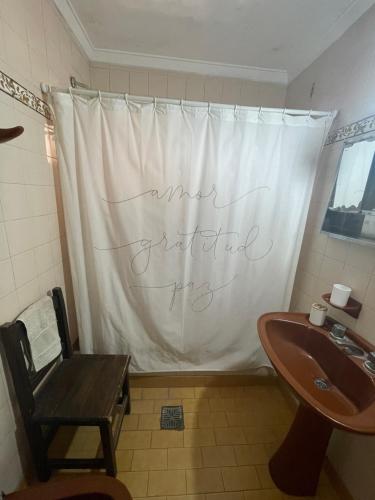 ein Badezimmer mit einem Waschbecken und einem Duschvorhang mit einem handschriftlichen Schild in der Unterkunft Departamento Tranquilo in Necochea