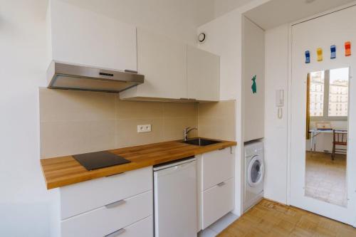 a kitchen with white cabinets and a washer and dryer at Centrally-located Studio Reuilly-Diderot in Paris
