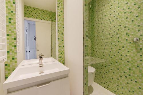 a bathroom with a white sink and green tiles at Centrally-located Studio Reuilly-Diderot in Paris