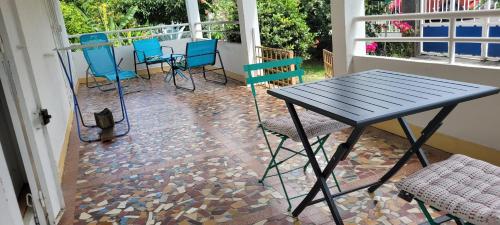 a patio with a table and chairs on a porch at logement accès piscine in Basse-Terre