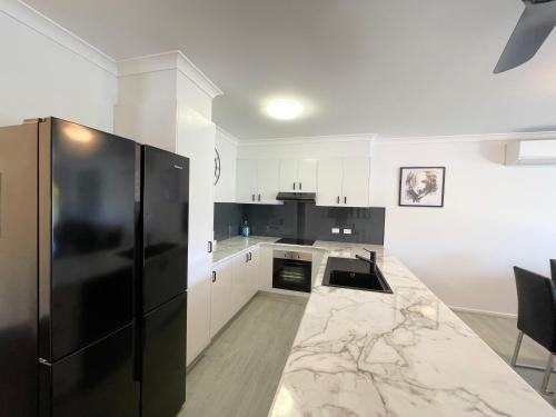 a kitchen with a black refrigerator and white cabinets at Oceanic on Thompson Apartments in Cowes