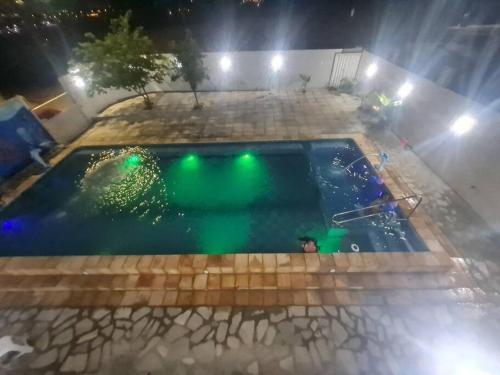 an empty swimming pool at night with green lights at Casa mobiliada para hospedagens e com piscina para o lazer in Bayeux