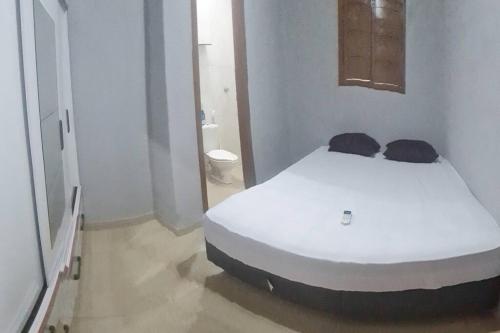 a white bed in a room with a bathroom at Casa mobiliada para hospedagens e com piscina para o lazer in Bayeux