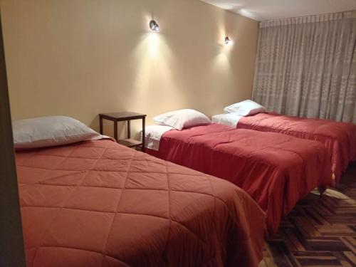 duas camas num quarto de hotel com cobertores vermelhos em HOSTAL SUIT ANDINA em Puno
