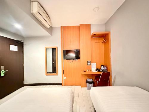 a hotel room with two beds and a desk at My Home Hotel Pontianak in Pontianak