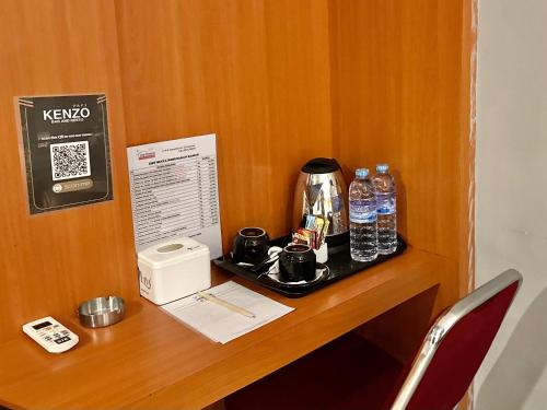 a desk with a coffee maker and water bottles on it at My Home Hotel Pontianak in Pontianak