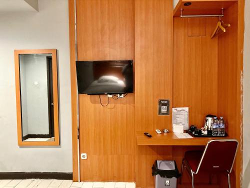 a room with a desk and a television on a wall at My Home Hotel Pontianak in Pontianak
