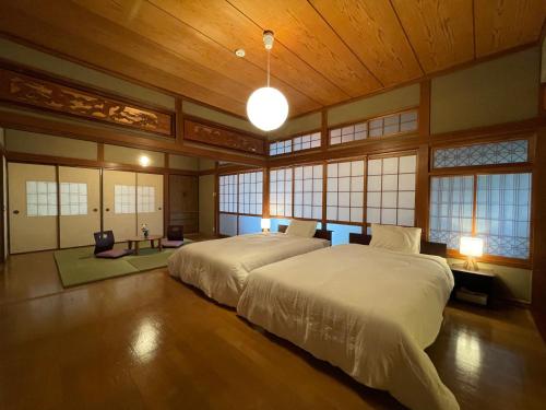 a bedroom with a large bed in a room with windows at 貸切宿KUMANO in Miyazaki