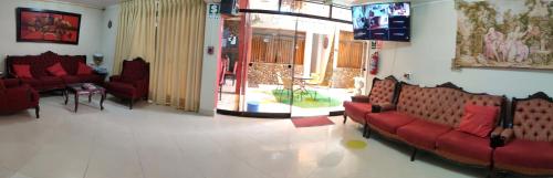 a waiting room with red couches and a tv at Krusty Hostel II in Huaraz
