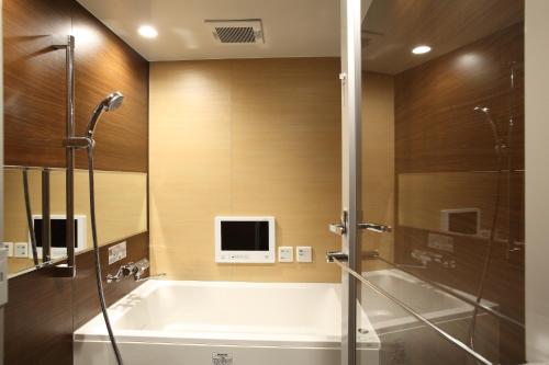 baño con bañera y TV en la pared en ホテルクリスタルゲート木更津, en Kisarazu
