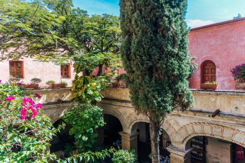 an old building with trees and flowers in front of it at Quinta Real Oaxaca in Oaxaca City